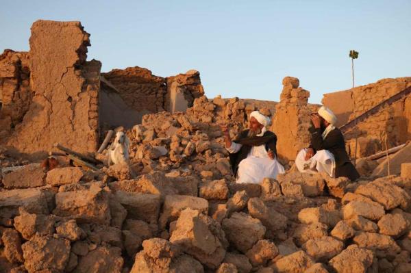 Men sitting on rubble after earthquakes destroyed western Afghanistan.